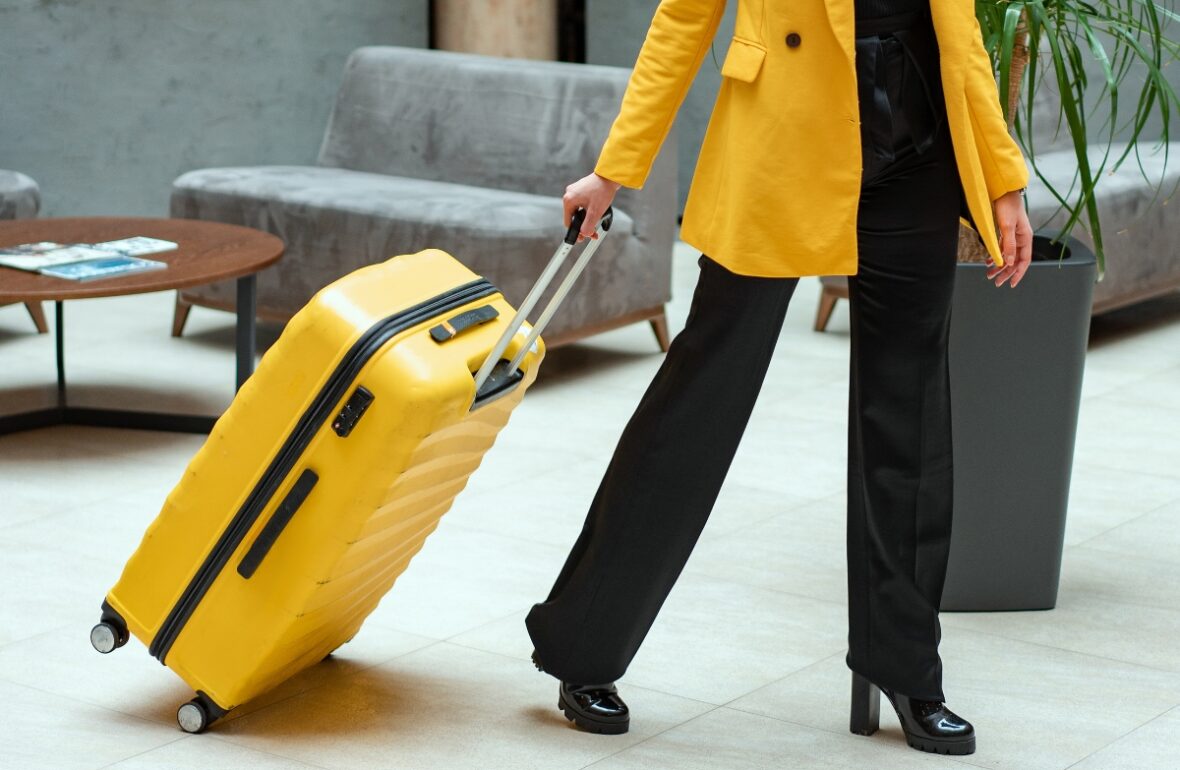 жінка в жовтому плащі везе жовту валізу