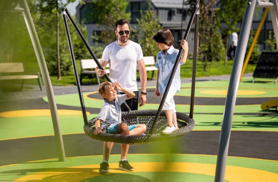 батько катає синів на качелі