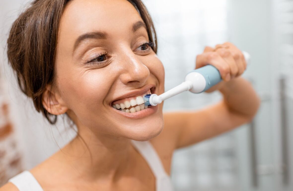 дівчина чистить зуби електричною зубною щіткою