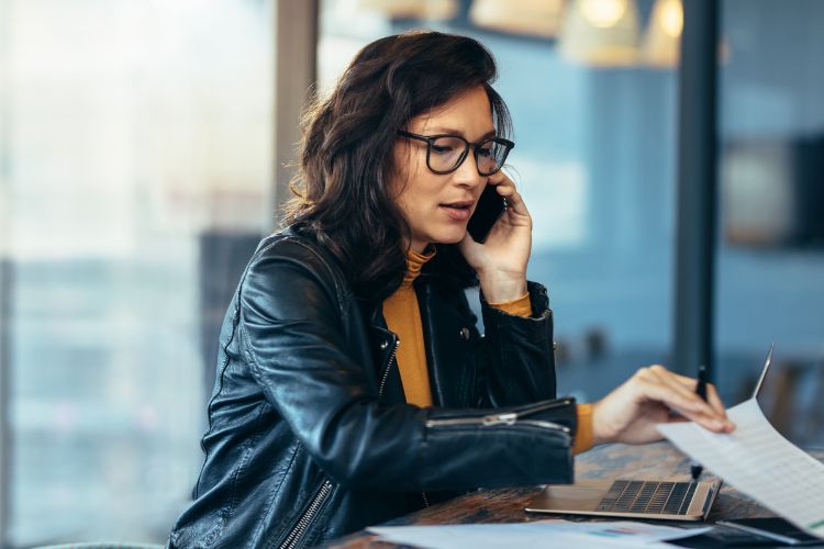 ділова жінка в офісі розмовляє по мобільному телефону