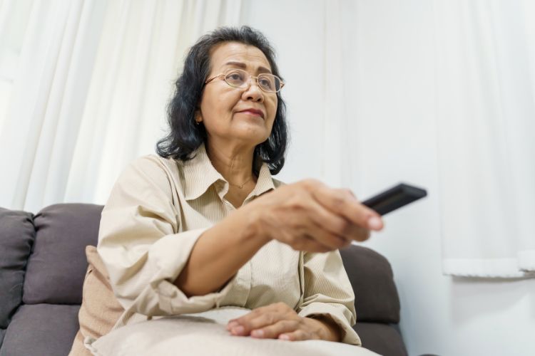 літня жінка в окулярах дивиться телевізор